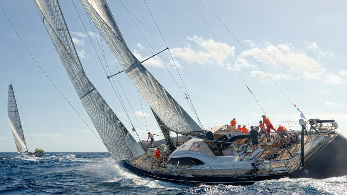 A massive sailing yacht, sails billowing in the wind, speeds through the water during a windy day at the Les Voiles De Saint-Tropez regatta.