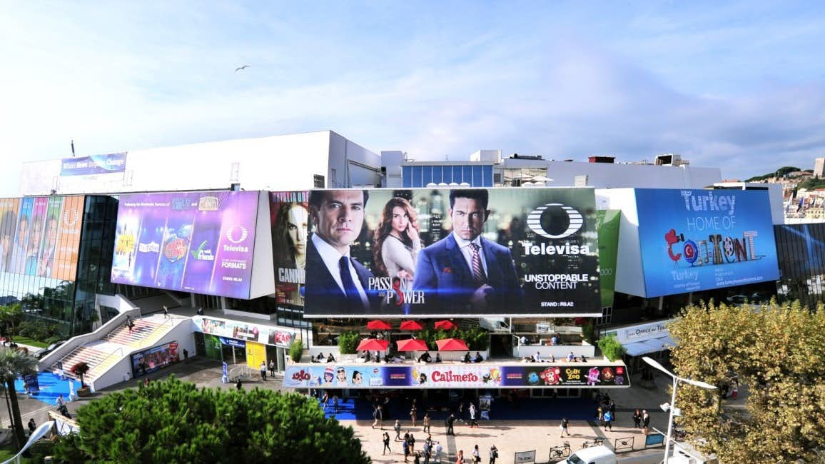 A picturesque view of the Palais des Festivals in Cannes, illuminated by the sun, with people entering the venue to attend MIPCOM 2024.