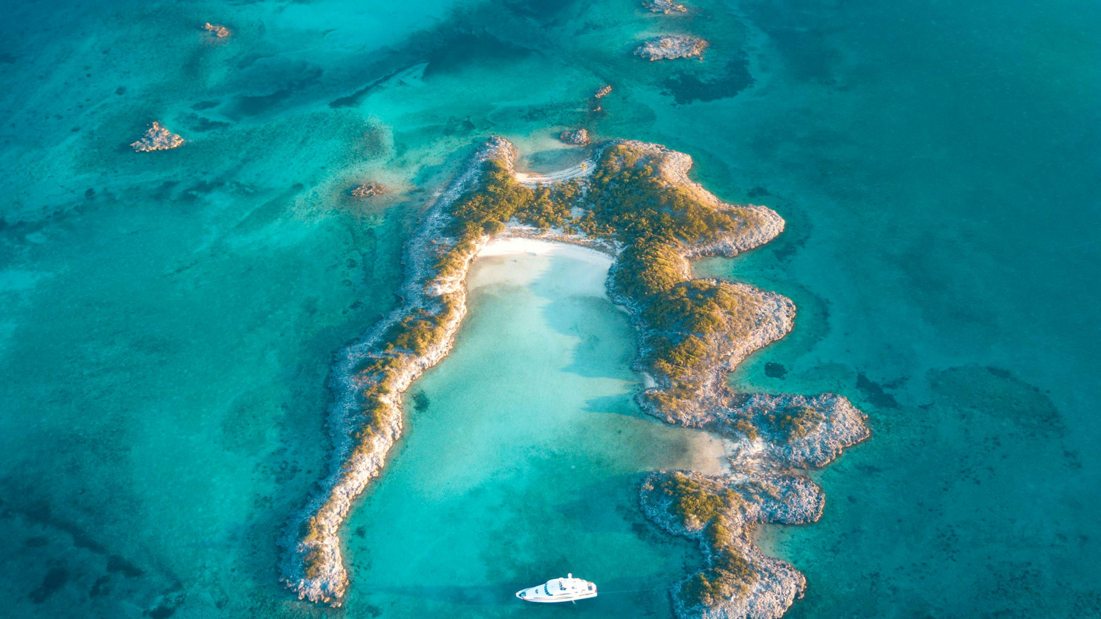 A luxurious yacht gracefully anchored off the shores of a tropical island in the Bahamas, surrounded by azure waters and lush greenery.