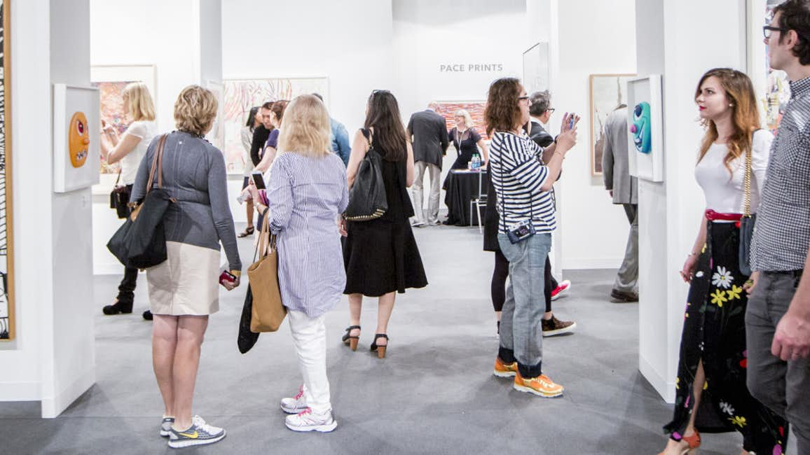 Visitors engaged in viewing and capturing the vibrant artwork on display at Art Basel Miami 2024.