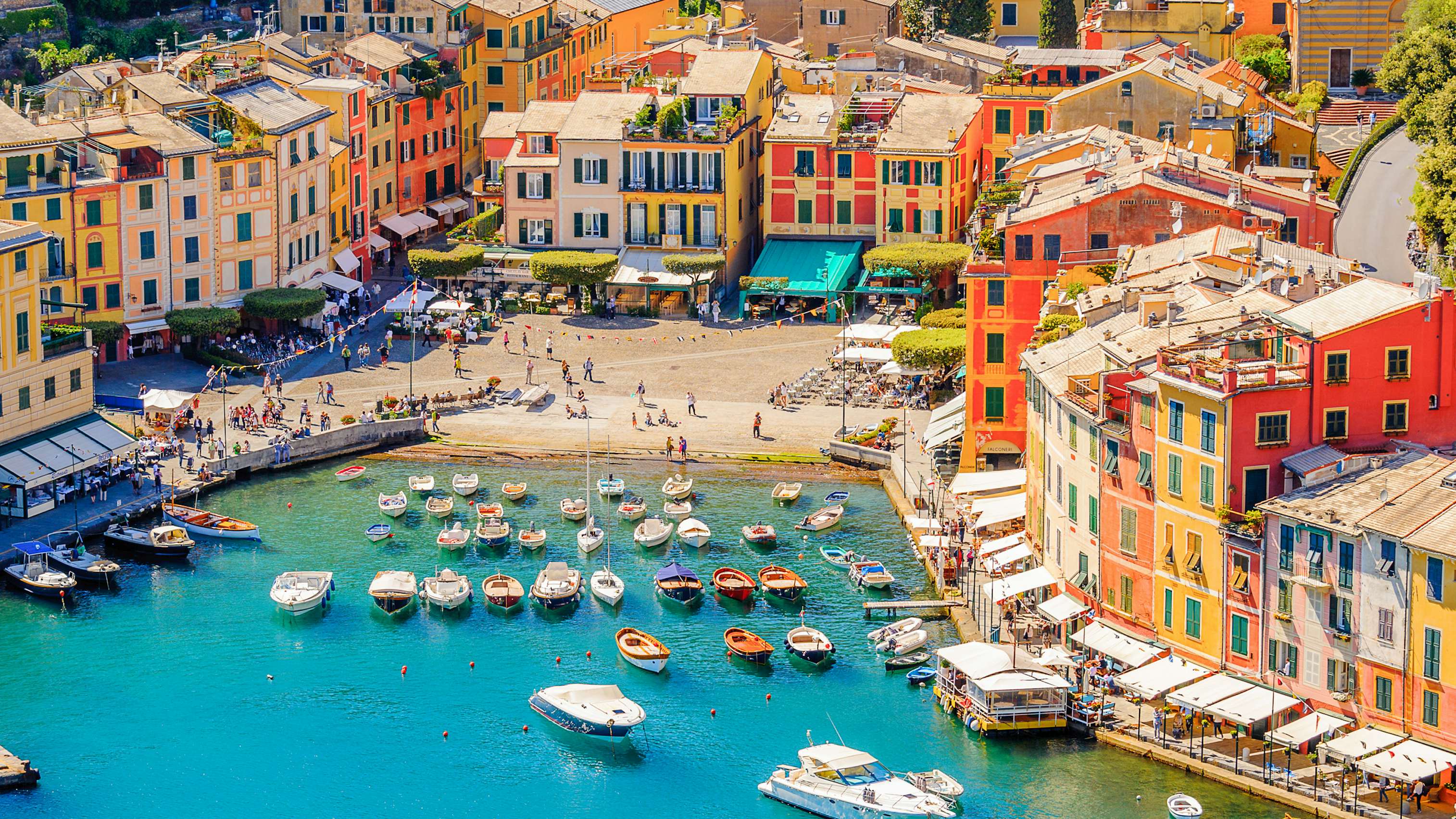 Vibrant harbor of Portofino with colorful buildings and luxury yachts, epitomizing Italian Riviera elegance.