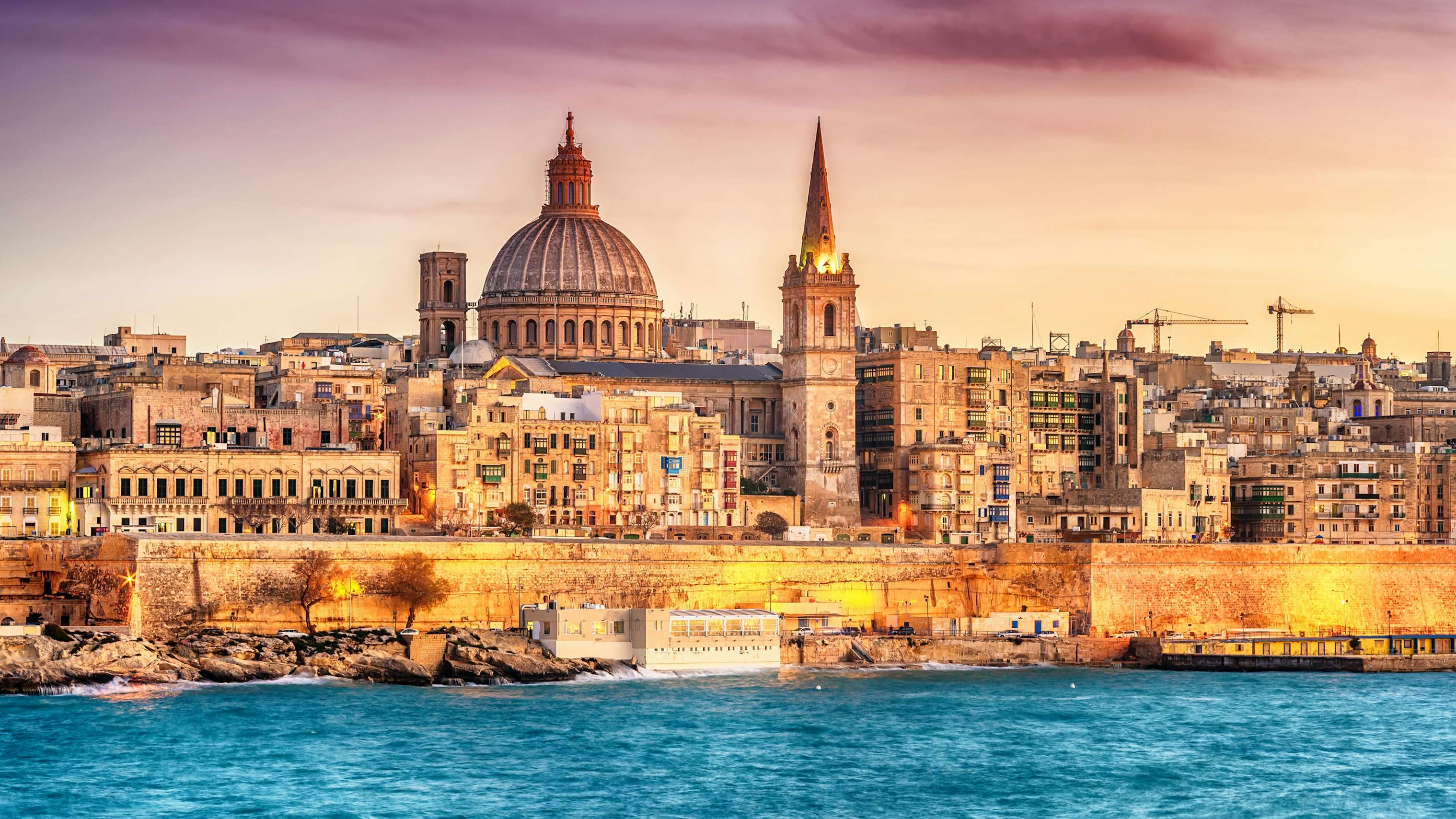 Historic Valletta skyline at sunset, with the iconic St. Paul's Cathedral dome, as viewed from a yacht.