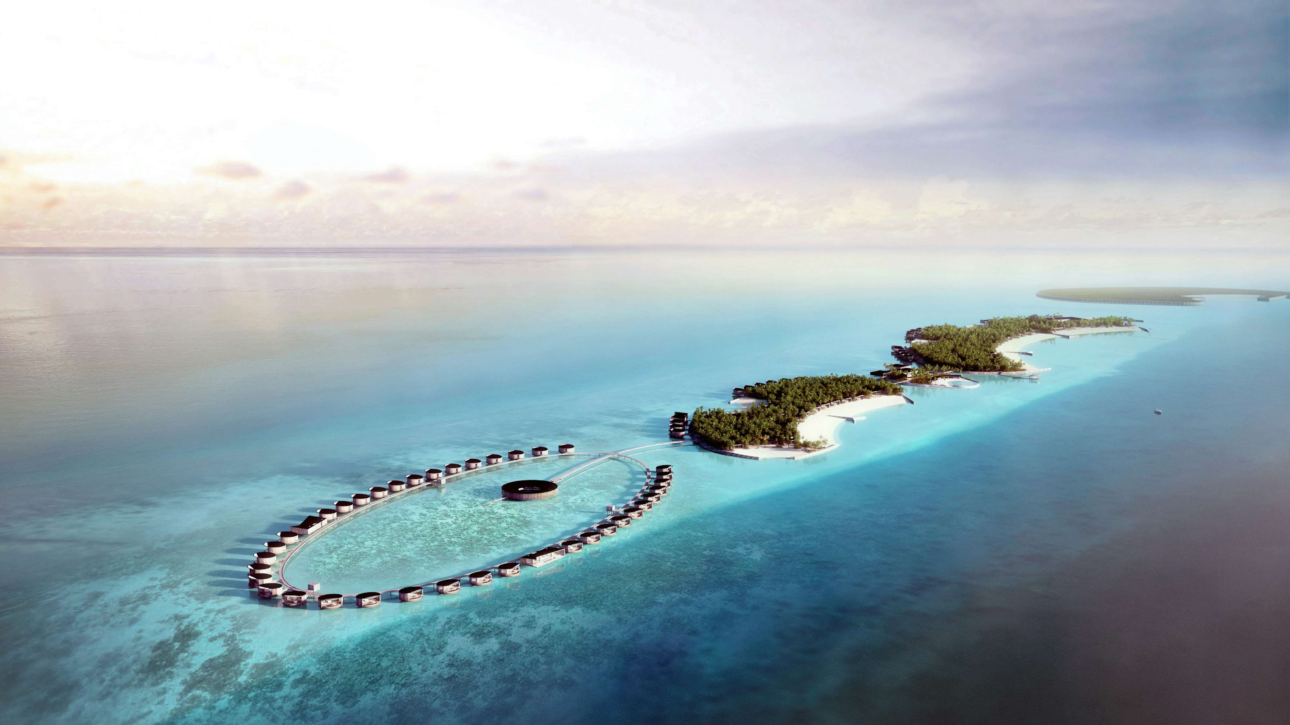 Aerial view of a circular coral atoll in the Maldives with a luxurious yacht anchored in the turquoise lagoon, surrounded by tropical greenery.